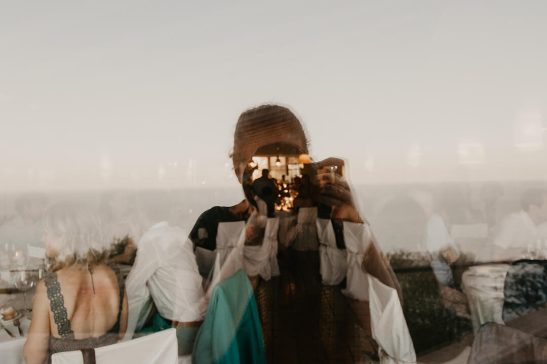selfie de la fotografa georgia porredon reflejado en una ventana haciendo unas fotografias de boda en la Costa Brava